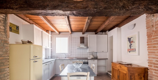 A kitchen with white cabinets, a wooden ceiling, and a tiled floor.