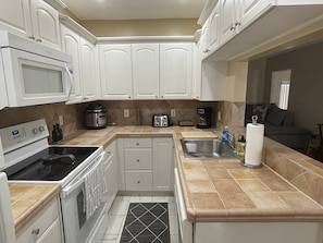A modern kitchen with white cabinets, a stove, microwave, toaster, and coffee maker.