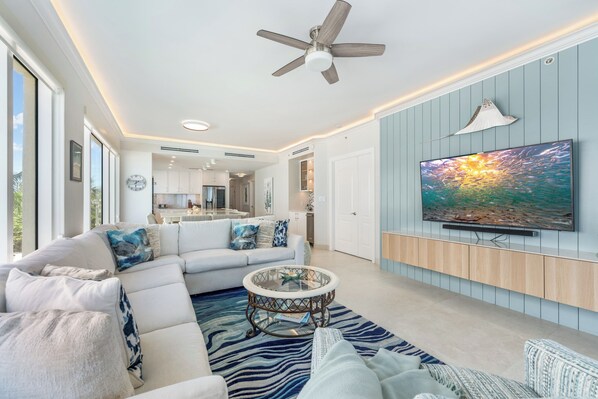 Una sala de estar moderna con un sofá modular, una mesa de centro de vidrio y un televisor de pantalla plana montado en la pared.