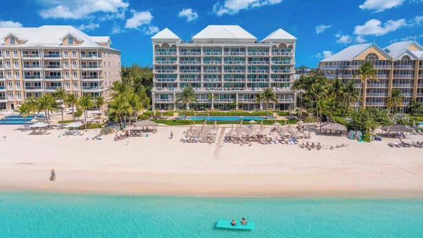 A resort with multiple buildings, a beach, and a pool area. - Beachcomber 19 by Grand Cayman Villas (7 Mile Beach)
