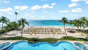 A resort pool with a view of a beach and ocean. - Beachcomber 19 by Grand Cayman Villas (7 Mile Beach)