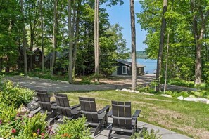 Un chalet au bord du lac, avec des fauteuils Adirondack et une vue sur l’eau.