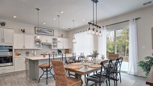 Una cocina moderna con armarios blancos, una isla central e iluminación colgante.