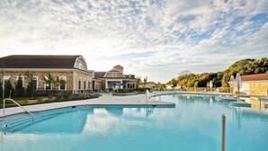 Zona de piscina con área de estar cubierta y un edificio de fachada de ladrillo.