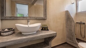 Une salle de bain avec un lavabo sur colonne blanc, un grand miroir, une douche et des toilettes.