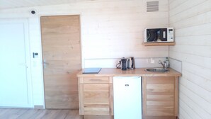 Cocina compacta con lavavajillas integrado, hervidor y lavabo pequeño.