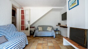 Ein Wohnzimmer mit einer Couch, einem kleinen Tisch, einem Fernseher und einem Kamin.