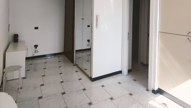 Habitación amplia con cama, una mesita y un espejo. Hay una puerta que conduce a otra habitación.