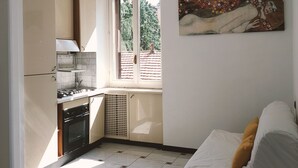 Una cocina compacta con ventana, un radiador y un cuadro en la pared.
