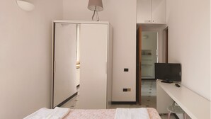 Una habitación de hotel con una cama, un escritorio, un televisor y un espejo.