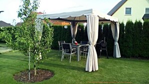 Área de pátio externo com mesa e cadeiras sob um toldo branco.