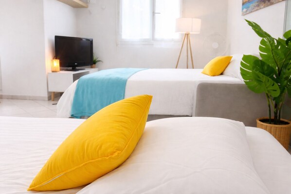 Een hotelkamer met twee bedden, een televisie, een lamp en een kamerplant.