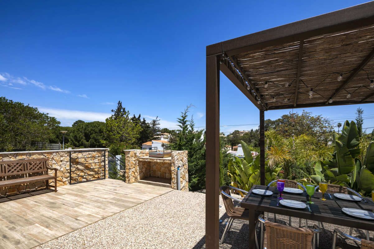 An outdoor patio with a stone fireplace, wooden furniture, and a table set for dining.