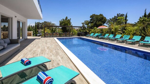 Una piscina con sillas de descanso y una zona cubierta.