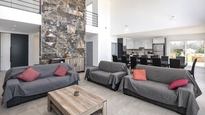 Amplia sala de estar con dos sofás grises, una mesa de centro de madera y una pared de acento de piedra.