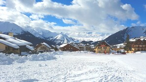Ein verschneites Dorf mit Häusern vor einer Bergkulisse.