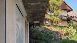 Ein Gebäude mit einem Schild, auf dem 'ENTREE' steht, und einer hölzernen Bank vor der Fassade.