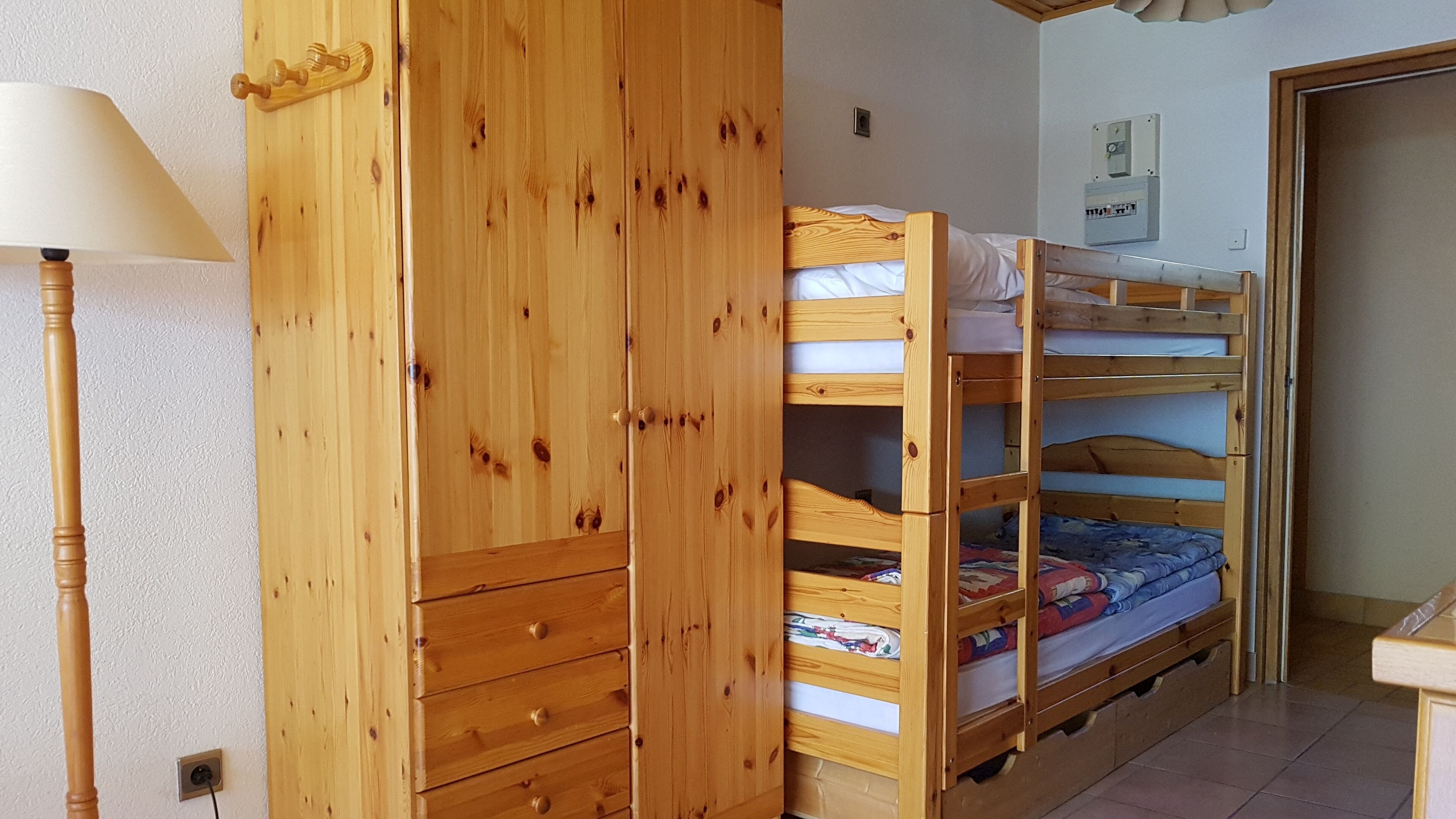 Un letto a castello di legno con un armadio e una lampada in una stanza.