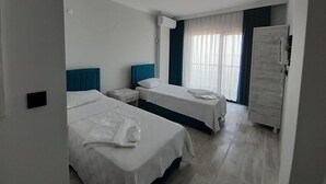 Ein Hotelzimmer mit zwei Betten, einem Nachttisch, einem Fenster mit Vorhängen und einer Tür.