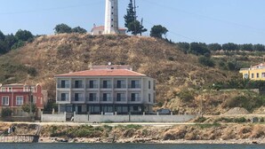 Ein Küstengebäude mit einem Leuchtturm auf einem Hügel, einer Anlegestelle und einem Wasserabschnitt.