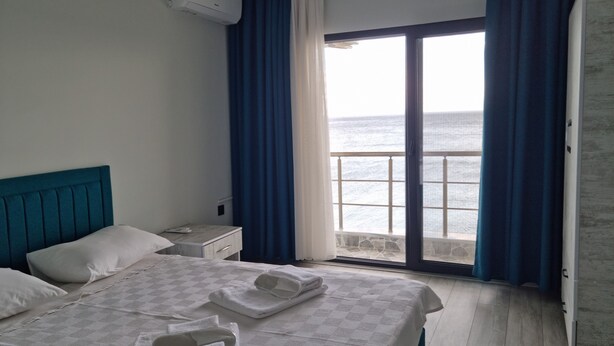 Ein Hotelzimmer mit Bett, Nachttisch, Fenster mit Meerblick und Tür.