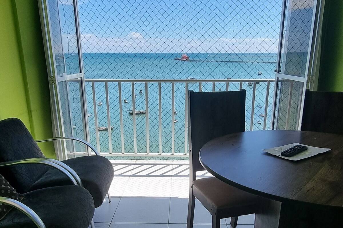 Un balcon avec une table et des chaises, une vue sur la mer et un mur végétal.