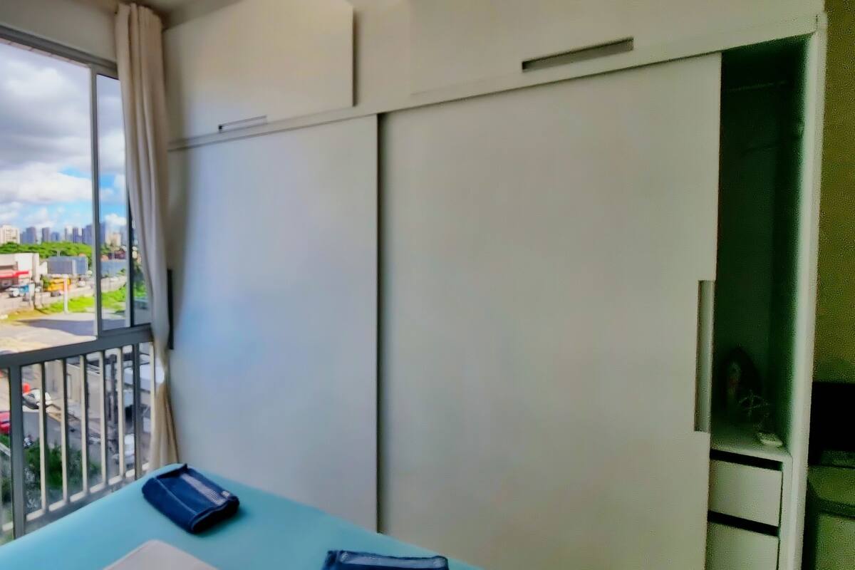 Un balcon donnant sur le paysage urbain, une table avec un carnet et une armoire.