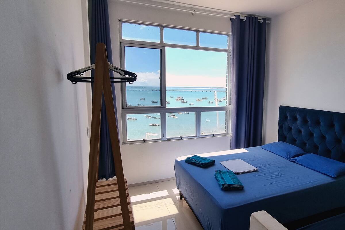 Une chambre à coucher avec un lit, une fenêtre donnant sur la mer et une échelle en bois.