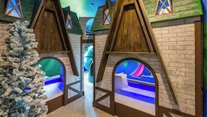 Un espace de jeux pour enfants avec des cabanes en bois et un sapin de Noël.