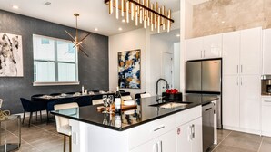 A modern kitchen with a central island, white cabinetry, and stainless steel appliances. - Stylish Home w/ Builder Themed BR, Arcade, Pool Table & Game Loft - Near Disney (Davenport)