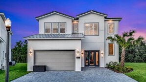 A two-story house with a garage, a well-maintained lawn, and a street lamp. - Stylish Home w/ Builder Themed BR, Arcade, Pool Table & Game Loft - Near Disney (Davenport)