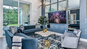 A modern living room with a sectional sofa, a coffee table, and a TV mounted on the wall. - Stylish Home w/ Builder Themed BR, Arcade, Pool Table & Game Loft - Near Disney (Davenport)