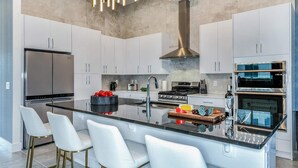 A modern kitchen with white cabinetry, a stainless steel refrigerator, a gas stove, and a built-in oven. - Stylish Home w/ Builder Themed BR, Arcade, Pool Table & Game Loft - Near Disney (Davenport)