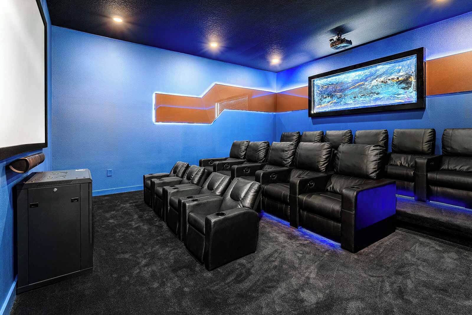 A home theater room with a blue wall, a large screen, and black leather seating.