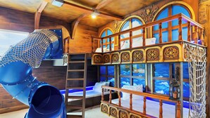A play area with a slide, a ladder, and a bunk bed with decorative windows.