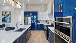 A modern kitchen with blue cabinets, stainless steel appliances, and a white countertop.