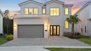 A modern two-story house with a garage, large windows, and a well-maintained lawn. - Stylish Home Near Disney w/ Secret Gaming RM, Pirate BR, Theater & Pool Table (Davenport)