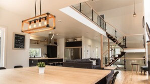 Een moderne keuken met een houten eettafel, een inbouwfornuis en een trap naar een hoger niveau.