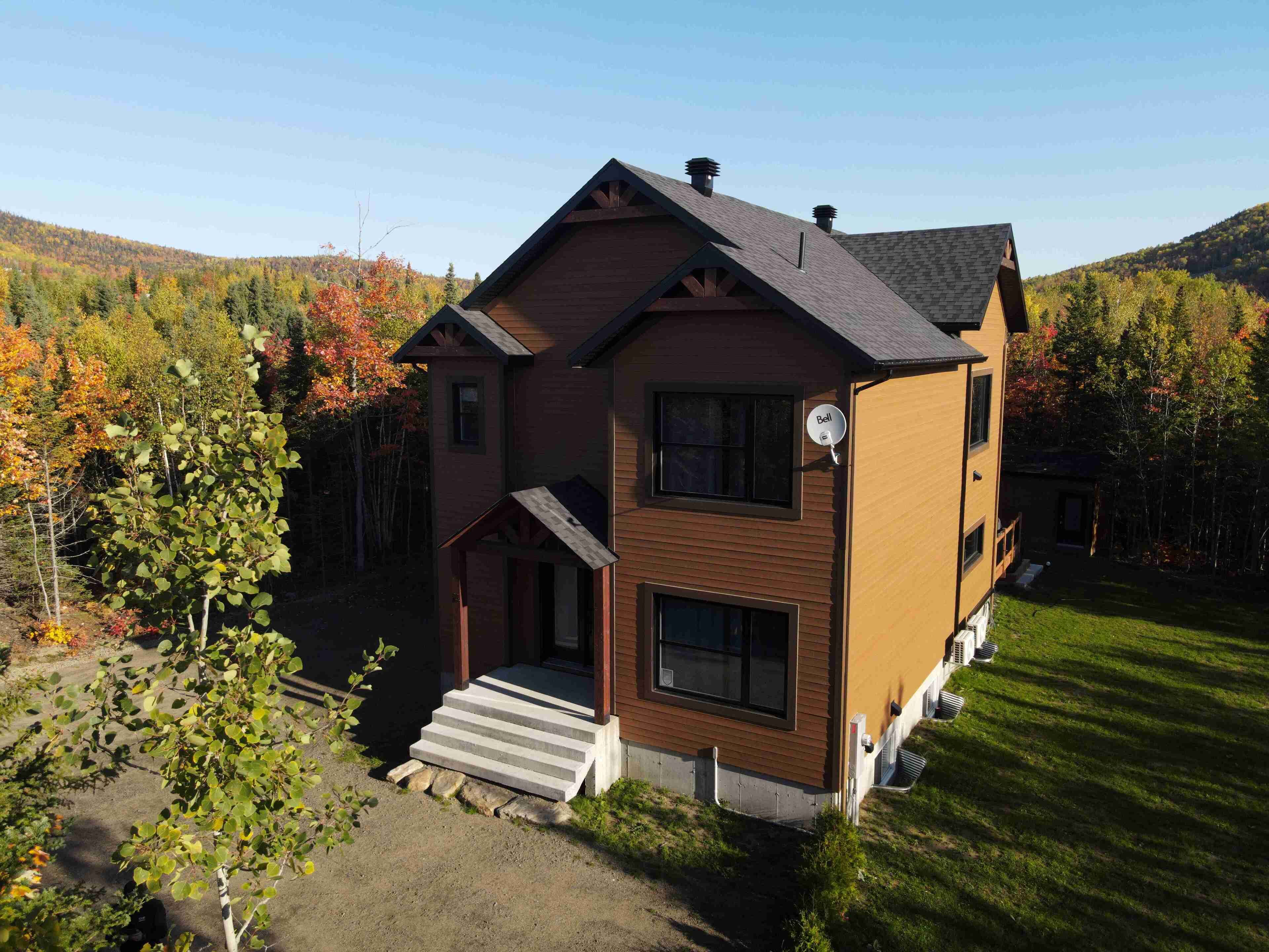 A two-story house with a sloped roof, a front porch, and a satellite dish.