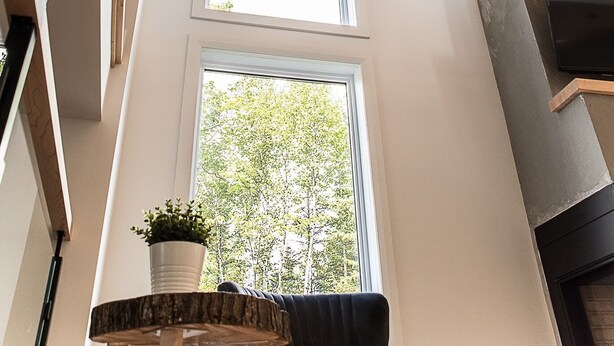 Een modern interieur met een hoge plafond, houten balken en grote ramen die natuurlijk licht doorlaten.