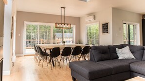 Een ruime woonkamer met een grote grijze modulaire bank en een houten eettafel omringd door stoelen.