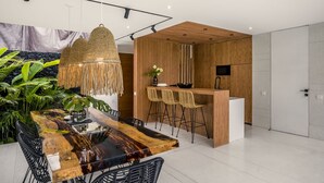 A modern kitchen with a wooden island, black chairs, and a hanging light fixture. - Green Flow Villa 16 (Ubud)