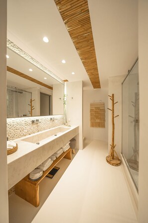 Une salle de bain moderne avec un grand miroir, deux lavabos et un plafond en bois.