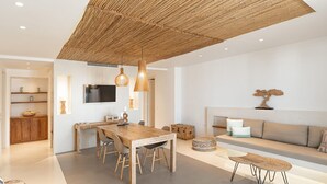 Een moderne woonruimte met een eethoek, een bank en een aan de muur bevestigde televisie.