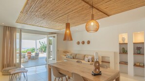 Een moderne eetruimte met een houten tafel en stoelen, een hanglamp en uitzicht op de omgeving.
