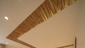 Een moderne slaapkamer met een groot bed, een houten hoofdbord, een bedlampje en een aan de muur bevestigde touwschommel.
