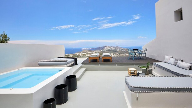 A rooftop terrace with a pool, lounge chairs, and a view of the city.