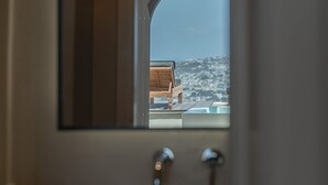 A bathroom with a large arched mirror reflecting a view of a chair and a pool.