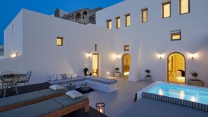 A modern outdoor living area with a pool, seating, and a view of the building's architecture.