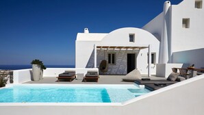 A modern white building with a pool, outdoor seating, and a view of the sea. - Exclusive One Bedroom Villa - White Co (Santorini)
